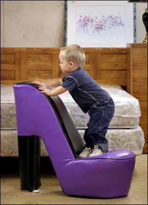 ROV bigshoe 01 - Gage Glass, 2, plays on a seat fashioned like a shoe, at the Saving Station, a used furniture and clothing store at 208 Paine Ave. in East Toledo whle his mother Candi shops. The Blade/Allan Detrich