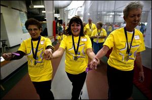 CTY relay 08p    Cancer survivors, Teresa Rossi, left, swings her hands with Jan Bain, center, and Bobbie Conour, right, during the first lap of American Cancers Society Relay for Life at Owens Community College Friday evening 4/8/05  in the gym at the Student Health and Activities Center.   The Blade/Madalyn Ruggiero