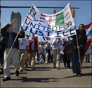 Robert Torres, left, of the Office of Latino Affairs and Michael Haack, 16, carry their flag in the march. 