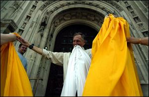 Jim Troknya gets help installing a 20-foot bunting on the doors of Rosary Cathedral after the election of Pope Benedict XVI.