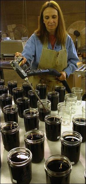 Connie Bowser, of Delta, pours candles into jars at Swan Creek Candle Co. in Swanton. 