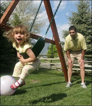 Joe Assenmacher watches his 2-year-old daughter, Olivia, swing on the play set the family bought
last month.  There has not been a day we have not been on the swing set,  Dr. Assenmacher says.