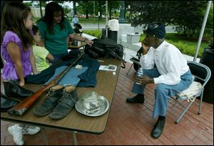 From left, Emily, Rachel, and mom, June Howland, discuss Civil War uniforms for African-American soldiers who fought for the Union with re-enactor Richard Trench at the museum.