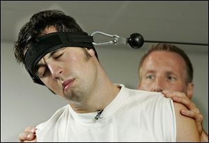 Sam Hornish Jr. works his neck muscles with help from trainer Jim Leo in his home in Napoleon.