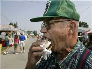 Vic Herringshaw of Rudolph enjoys a pork-a-lean sandwich at the fair in Bowling Green. 