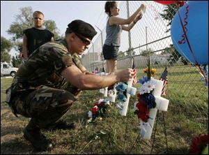 Eric Lynn and his wife, Amanda, place military prayer cards as their son, Eric, Jr., watches outside the Marine Corps reserve center in Brook Park, Ohio, home of the 3rd Battalion, 25th Marines.