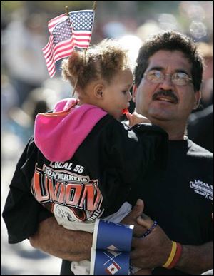 Olivia Montgomery, in an Ironworkers Local 55 shirt, is boosted up to watch the parade by Domingo Valadez.