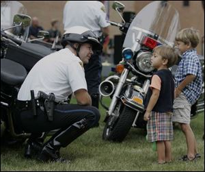 Cuyahoga Community College police Officer John Buettner, left, talks to children on hand for Ms. Young's departure.