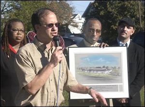 Terry Glazer speaks at Austin and Elm streets as, from left, Julia Bryant, the Rev. Clinton Dudley, and the Rev. Will Stuart look on with a picture of a proposed community center.
