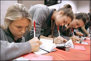 Notre Dame students Brittany Bodi, left, Elizabeth Stoiber, and Erin Berk write checks for incomes taxes as part of Finance 101 day designed to expose students of the demands of earning and spending money on a budget.
