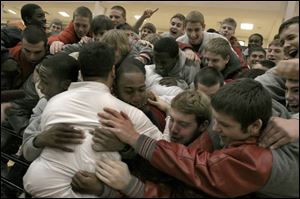 Members of Central Catholic's football team mob their coach, Greg Dempsey, following a rally yesterday to celebrate the state championship they won on Friday night.