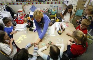 Pemberville Elementary School second-grade teacher Barb Brough conducts a game of Dollar Rummy with part of her math class last Thursday. The educational game is designed to teach students how to do addition by using number cards to add up to a dollar.