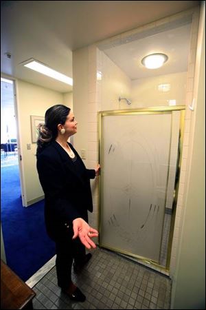 Amy Finkbeiner, the wife of Mayor Carty Finkbeiner, points out the shower stall on the 22nd floor of One Government Center that has led to heated criticism of her husband. The mayor says the shower will enable him to save time by showering at work after working out during his lunch hour.