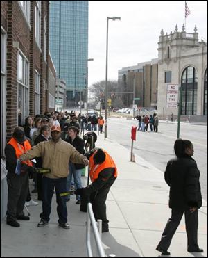 Guards scan the applicant at the head of the long line across from The Blade Building.