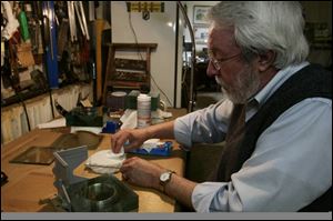 In the workshop, temporary apprentice Homer Brickey polishes a sheet of glass to be added to the growing cube.