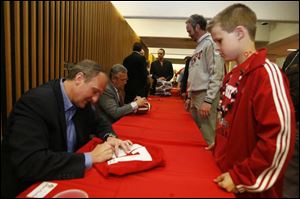 Ohio State basketball coach Thad Matta signs a jersey for Derek Schult, 12, of Waterville, while football coach Jim Tressel signs a football for Derek's father, Steve, at 