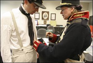 Tamia Land of Northwood sews suspenders into Blade staff writer Ryan E. Smith's uniform as he prepares for a re-enactment of Dudley's Defeat at Fort Meigs.