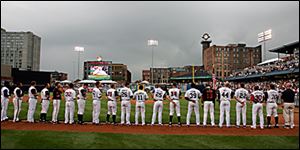 The International League lines up on the third-base line at Fifth Third Field for the Triple-A All-Star Game as the National Anthem is sung by Art Joslin, a soloist with the Toledo Opera.