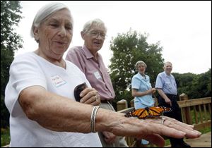 Mary Pat Anderson reacts to a monarch that rests on her hand while her husband Tom and Alice and Richard Edwards watch.