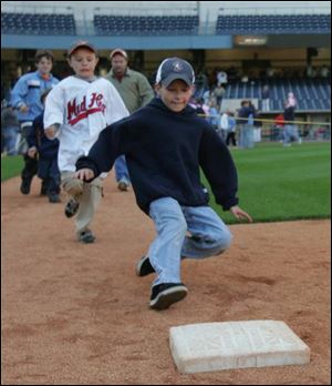 At left, Toledoan Jack Sniderhan, 8, slides into first base during the evening celebration recognizing the team's second Governors' Cup title in a row.