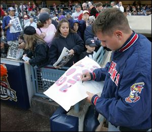 Mud Hens relief pitcher Preston Larrison signs autographs for fans from the dugout during the Mud Hens championship rally at Fifth Third Field. 