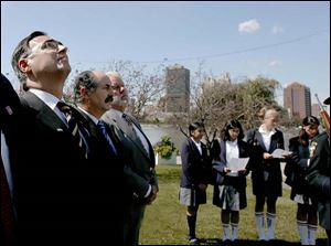 Jose Manuel Molina Garcia, the mayor of Toledo, Spain, at left, watches the flag-raising ceremony yesterday in International Park. Spanish offi cials began a five-day visit Saturday.