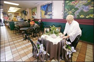 Mary Jo Stoyanovich adjusts the tables at Village Bistro in preparation for a period tea party.