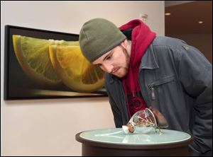 Student Robb Nardecchia examines a piece of art by Amanda
E. Stark in the faculty exhibit in BGSU s Fine Arts Center.