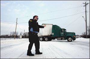 Perrysburg police Sgt. J.D. Justus stops traffic on State Rt. 25 so a semi that had been stuck can back up and go on its way.