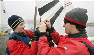 Kayleigh White of the University of Michigan team, left, from Monroe, joins Ryan Lashaway, from Perrysburg, of Owens to install a batten on a sail at the regatta on the Ottawa River. Fifty college students had a boatload of fun sailing in yesterday's breezy, mild temperatures - this is the warmest weekend yet this year - during the first regatta ever hosted by Owens Community College.