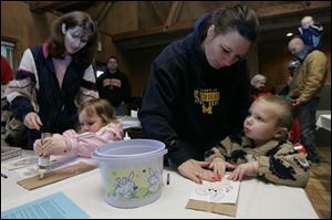 Shelly Taylor and her daughter, Nicole, 3, left, of Sylvania, and Tammy VanHorn and her son Donovan, 3, of Lambertville decorate their egg bags during the hunt at Ottawa Park.