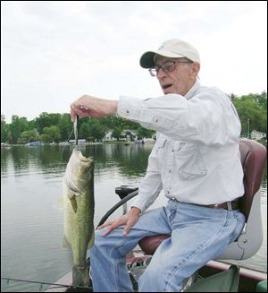 Marion Garber, a veteran bass fisherman from Temperance, Mich., hefts a largemouth bass hooked on Evans Lake in the Irish Hills, using a treble-hook-filled crankbait. A Rattlin' Rogue is a popular and successful bass crankbait.