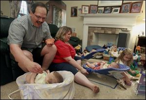 Bernie and Amy Gokey feed their triplets, Danel, left, Abigail, and Caleb, as daughter Lydia plays.