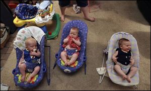 Caleb, left, Abigail, and Daniel Gokey wait for their parents to feed them.