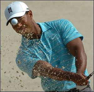 The sand fl ies as Tiger Woods hits out of the sand trap at the No. 8 hole during the opening round of the U.S. Open.
