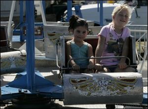 De-Laciana Martinez, 3, left, and her cousin Abby Speiker of Cocoa, Fla., take a spin on one of the rides at the festival. Tasting the strawberry treats is part of the fun in Community Homecoming Park.