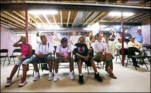 Steffanye Hicks, Shaquille Clemons, Antonia Draper, Jordan Walker, and Lori Shaw, from left above, of Englewood Peace Robotics Engineering Team, listen during a presentation in the basement of an energy-efficient house.