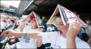 Marc Green of Toledo, left, and Matthew Wunder of Perrysburg used their programs for shade at yesterday s Mud Hens game.
