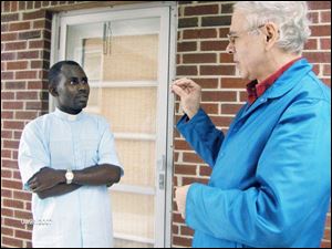 Louis Tillie, right, who is deaf, uses sign language to communicate with Ghislain Cheret Bazikila, a  eminary student in San Francisco who is spending the summer working in the Toledo diocese. Mr. Bazikila  was meeting with Mr. Tillie and his mother, who are members of the Toledo diocese s deaf community, at Medilodge Nursing Home in Monroe, Mich.