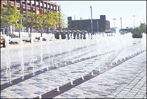 Jets of water shoot from a ground-level fountain on Detroit s new 3-mile-long RiverWalk.