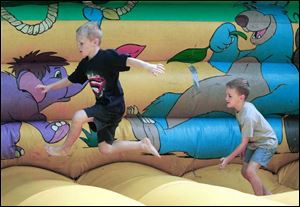 Grant Donald, 7, and his brother Drew, 6, from left scramble on one of the inflated amusement areas.