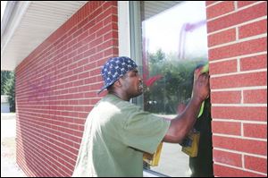 Jeremy White of Toledo removes a swastika from a window at the Toledo Islamic Academy High School. Six windows were painted with red swastikas and two windows were shot with what authorities believe was a BB gun. The school's entrance doors and some trees on the property also were defaced by vandals.