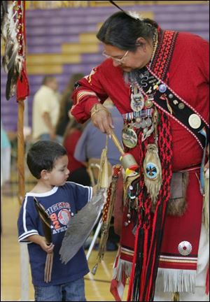 Nesyre Plain takes a close look at the gear of Richard Snake, of Alanson, Mich. The gathering, which includes several tribal nations and ends today, is at Maumee High School. 