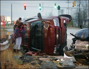 A woman, at left, wraps herself in a blanket and tries to keep warm at the scene of a fatal accident on southbound I-280 near the entrance to the Ohio Turnpike