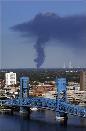 A plume of smoke rises in the distance north of downtown Jacksonville, Fla., after an explosion and fire at  T2 Laboratories.