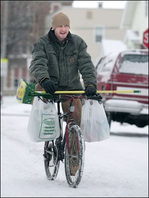 ROV snow02p 01/02/08 The Blade/Dave Zapotosky Matthew Smith bikes along snow covered Mott Ave., near East Broadway, after a trip to the store in Toledo, Ohio, on Wednesday, January 2, 2008.  He was carrying a new mop and some other cleaning supplies.