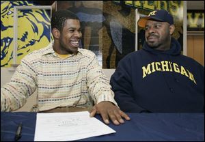 Tight end Kevin Koger is all smiles, along with his father, Carl, after signing his national letter of intent to accept a scholarship at the University of Michigan yesterday at Whitmer High School. 