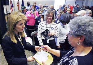 Caroline Kennedy, left, signs an autograph at the downtown library. She called Barack Obama as inspiring as her father.
