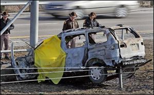 Iowa state troopers look over a burned-out van in which the body of a man was found yesterday. Police believe the body is that of indicted former bank executive Steven Sueppel.