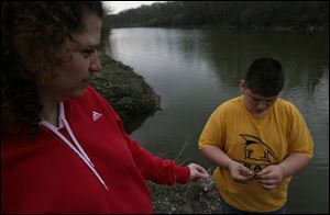 Sue Billingsley watches as Austyn Underwood, 13, of Oak Harbor puts a worm on her line so that she can fish in Silver Lake during the Welcome Back Walleye celebration in the park.